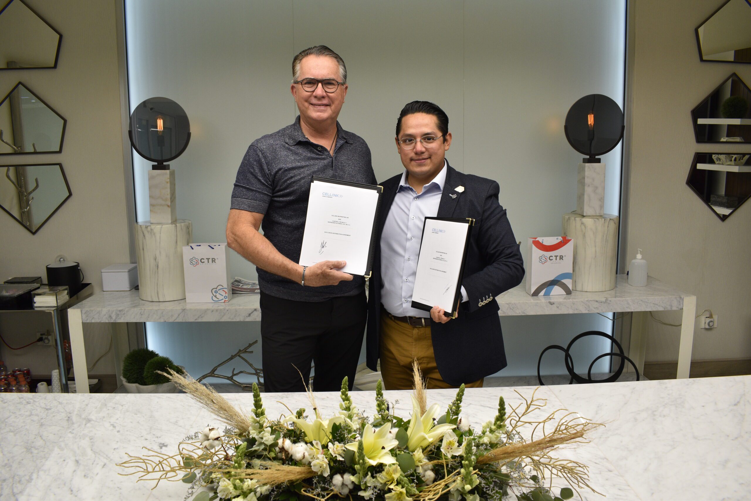 Two men celebrating the signing of a partnership between Mexican life science distributor CTR Scientific